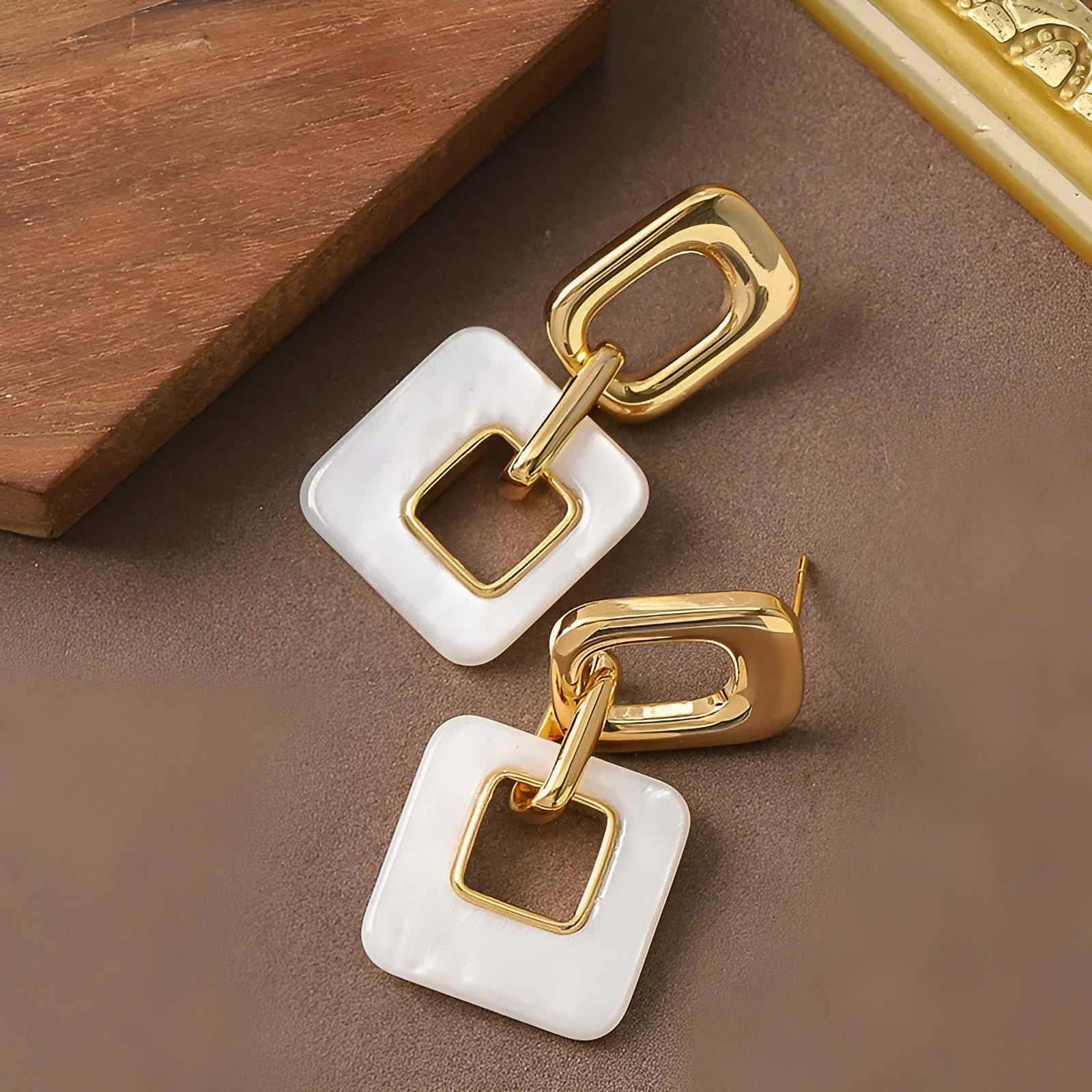 Dignified hollow geometric square copper earrings with electroplated finish on white background