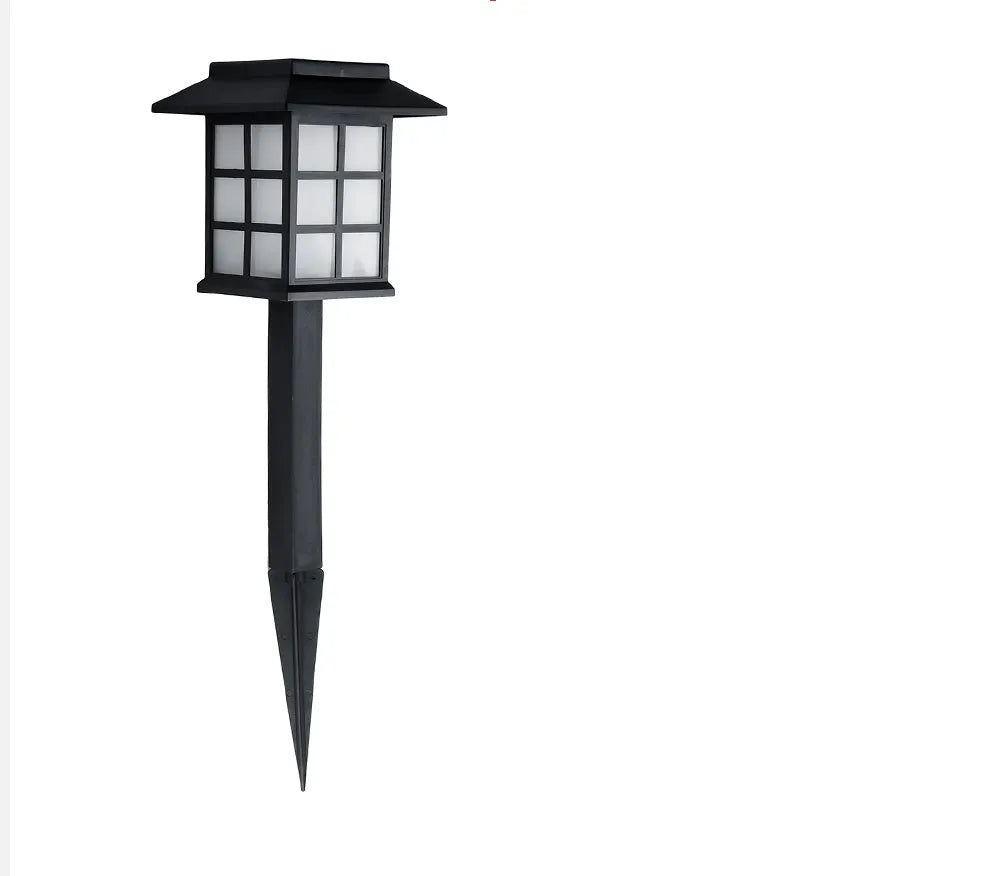 Black solar outdoor LED lawn light with decorative windows, IP65 waterproof, placed in a garden