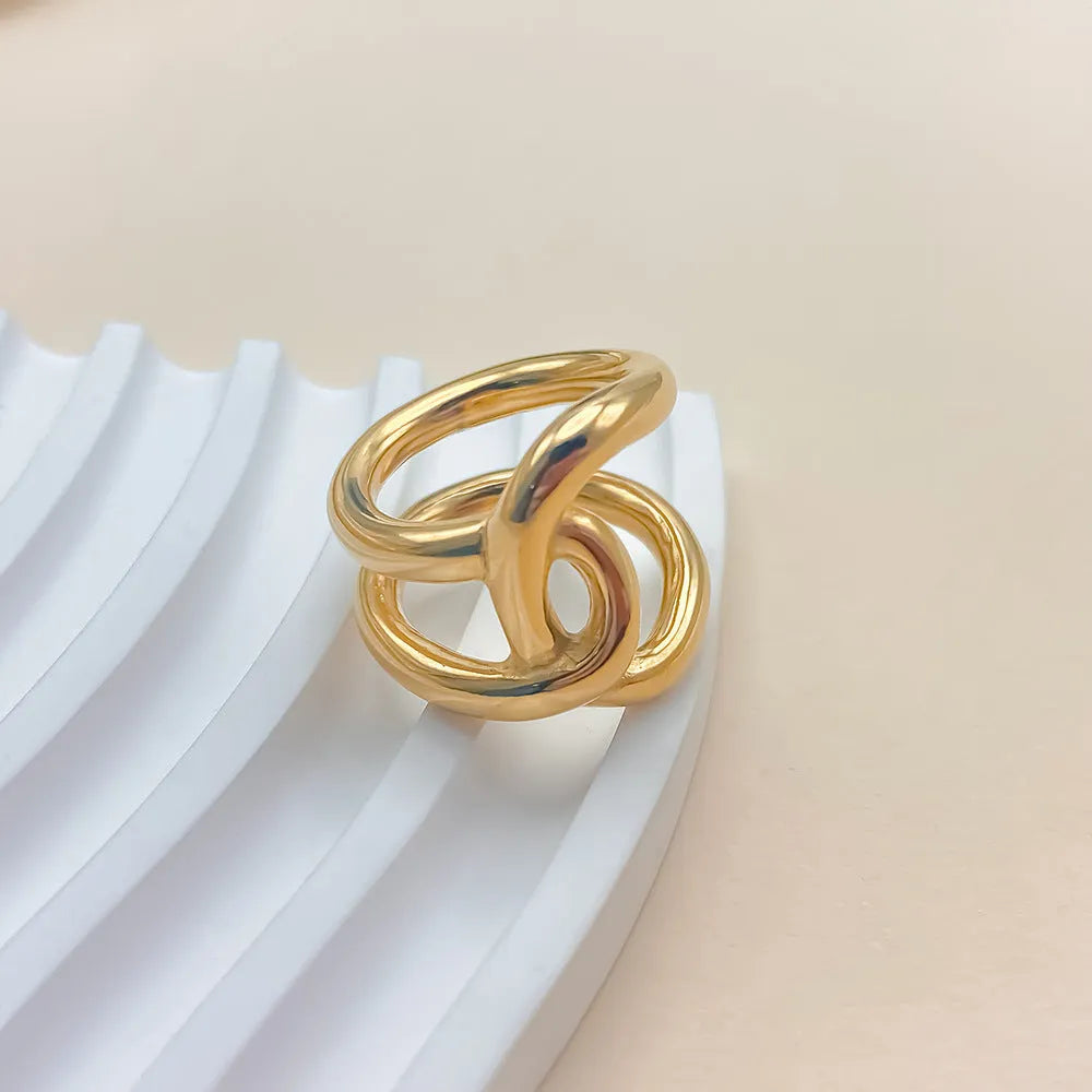 Adjustable knotted stainless steel ring in geometric U-shape, shown in gold and steel colours.