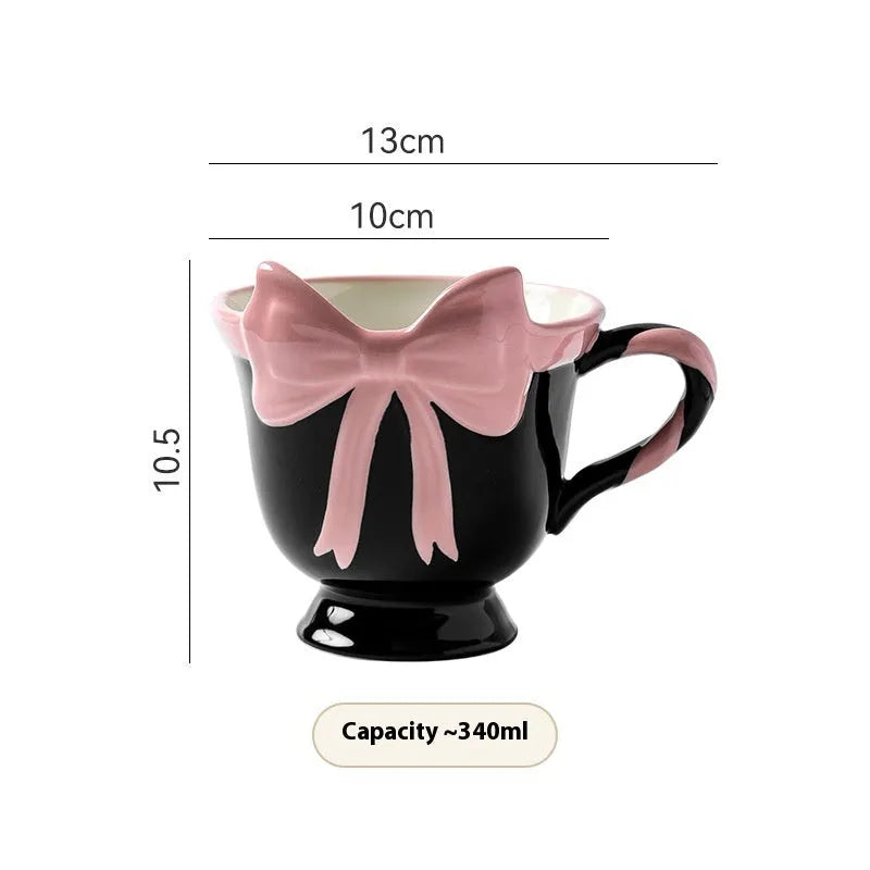 White ceramic mug with a pink heart and black bow design, 350ml capacity.