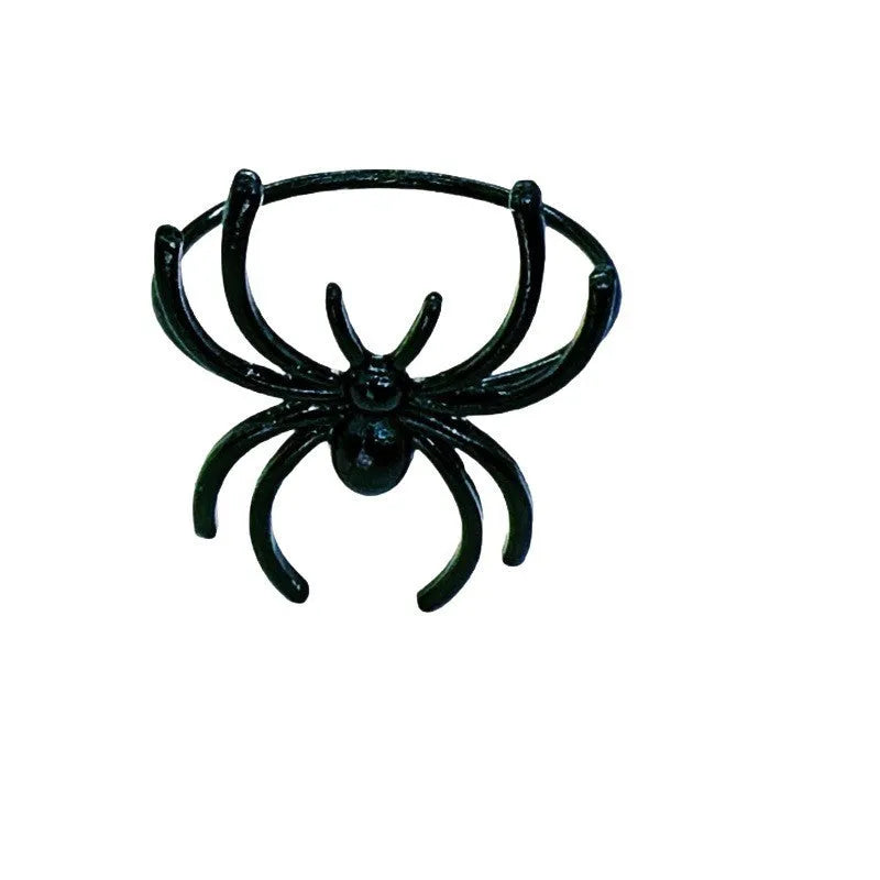 Six black alloy spider-shaped napkin rings for Halloween table decoration on a dark surface.
