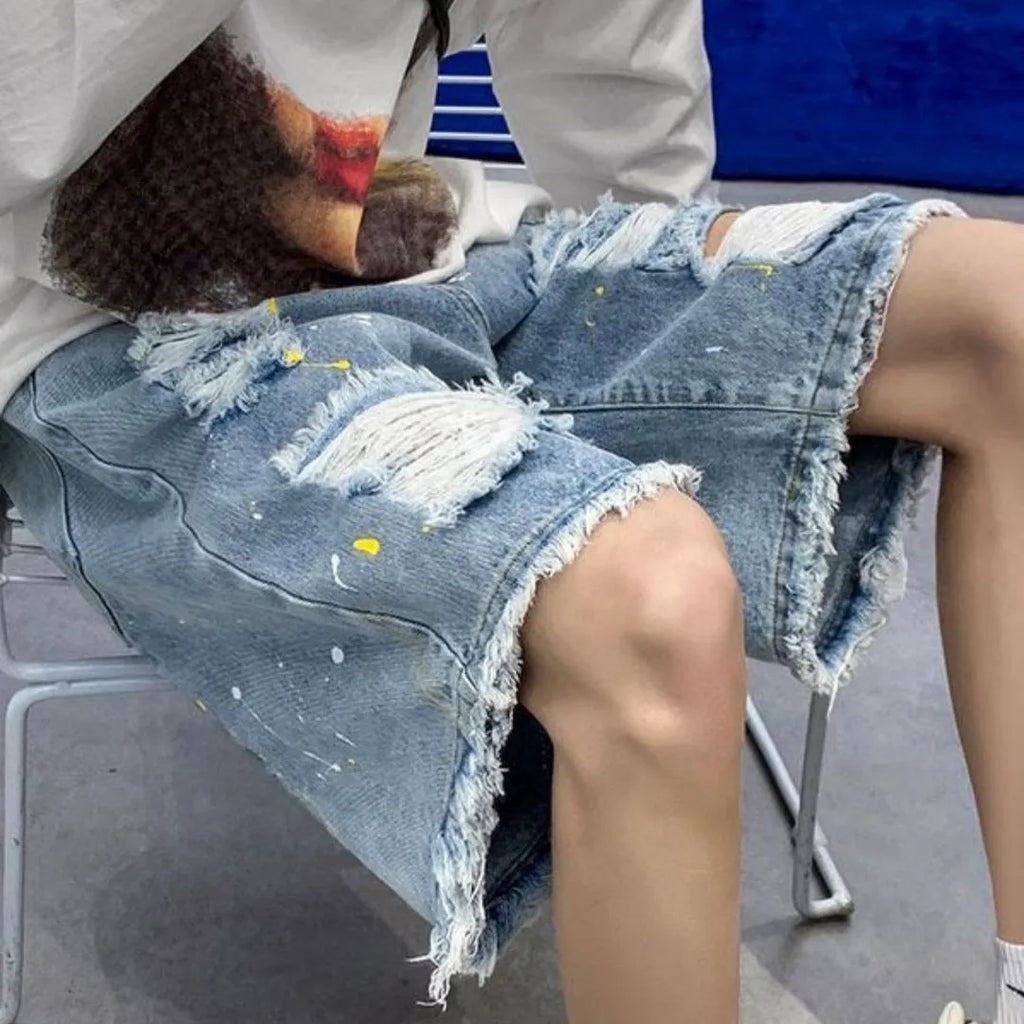 Men's loose fit denim shorts in light blue with water washed hole detail, laid flat.
