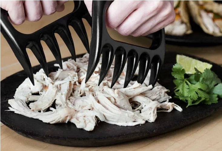 Two black PC plastic bear claw shredders for meat lying side by side on a cutting board