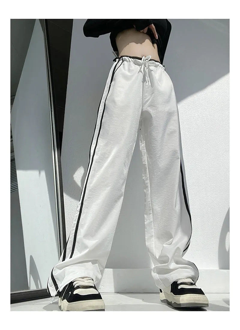 Navy blue loose straight-leg trousers with ribbon parallel bars contrast detail on a hanger.