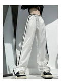 Navy blue loose straight-leg trousers with ribbon parallel bars contrast detail on a hanger.