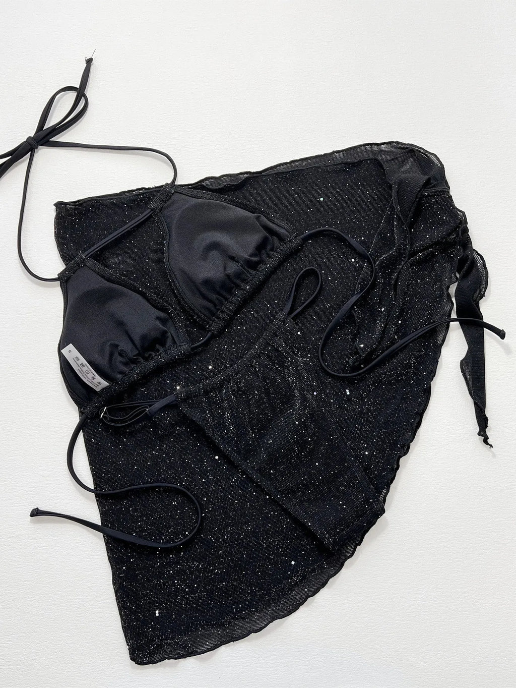 Black three-piece bikini swimsuit set with top and shorts on neutral background
