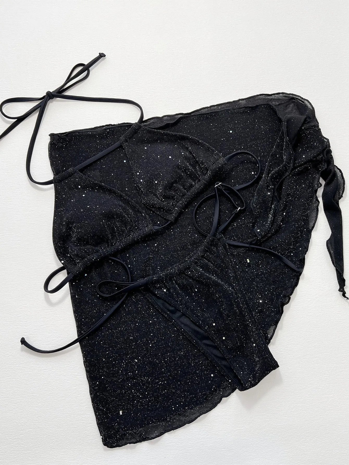 Black three-piece bikini swimsuit set with top and shorts on neutral background