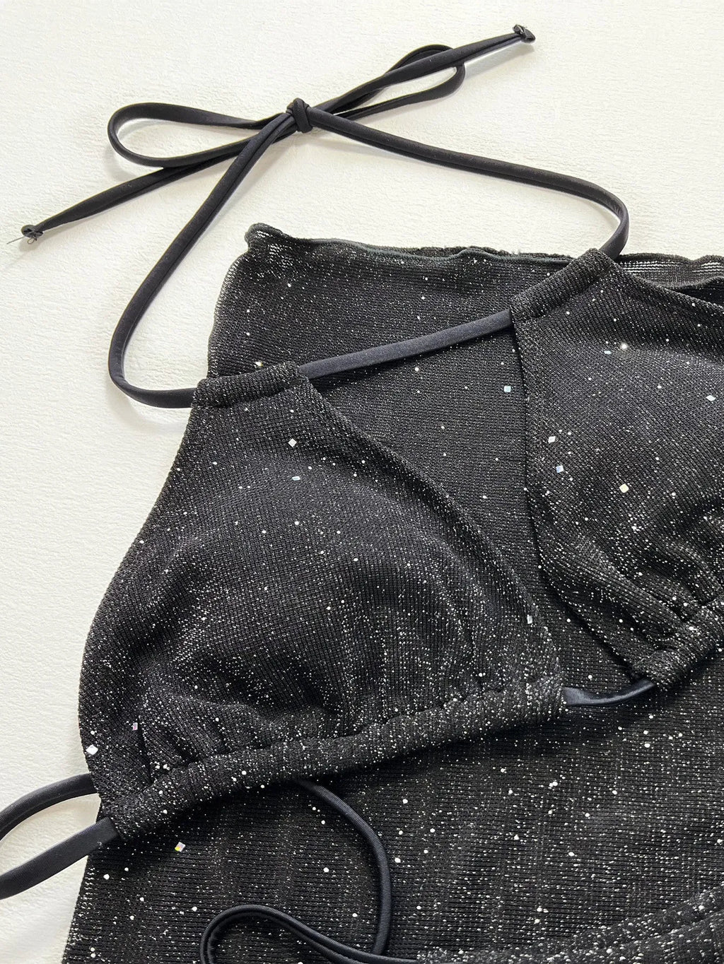 Black three-piece bikini swimsuit set with top and shorts on neutral background