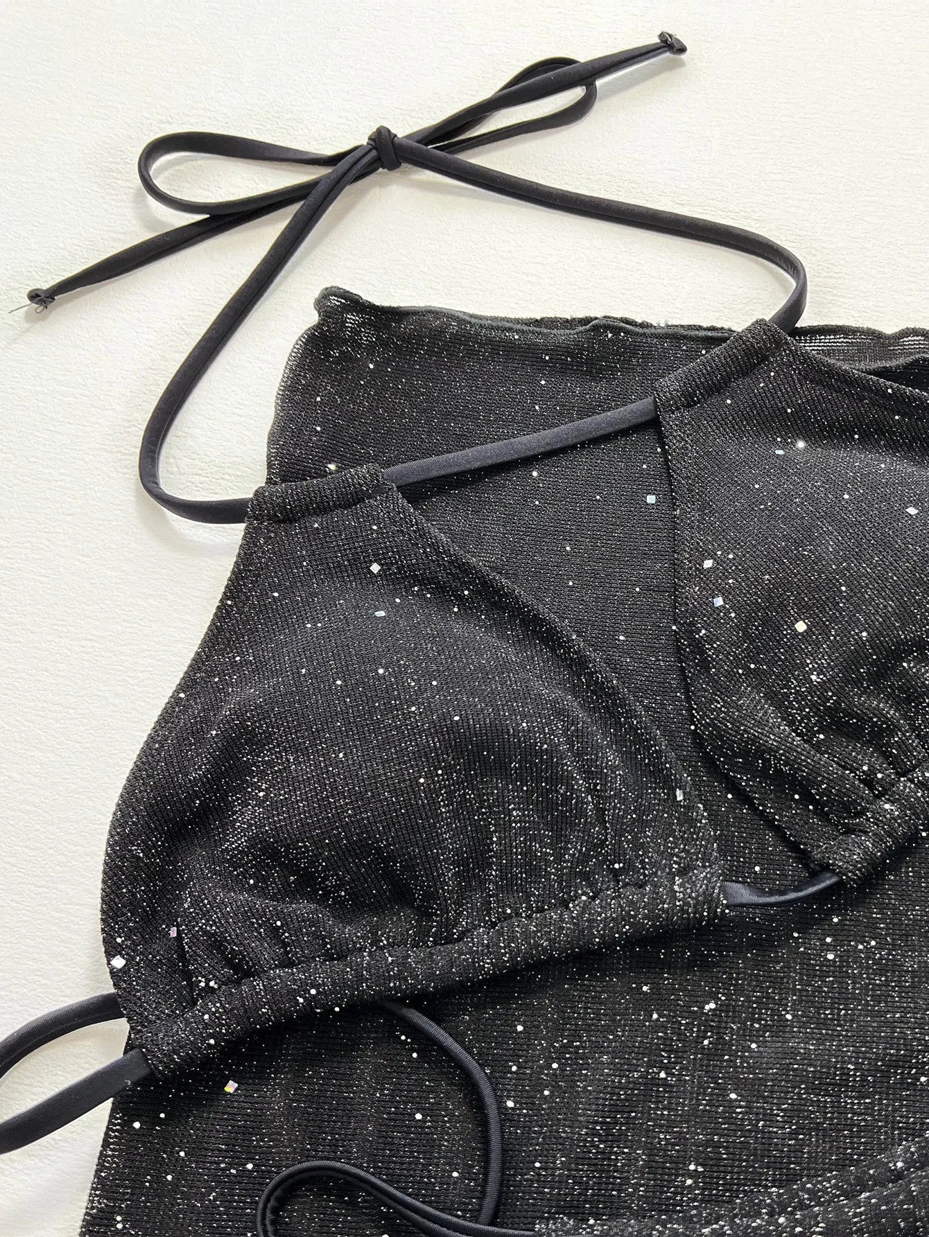 Black three-piece bikini swimsuit set with top and shorts on neutral background