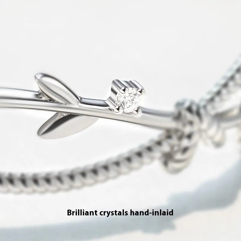 Cross twisted branch sprout bracelet in electroplated white gold Z4136 on a natural background