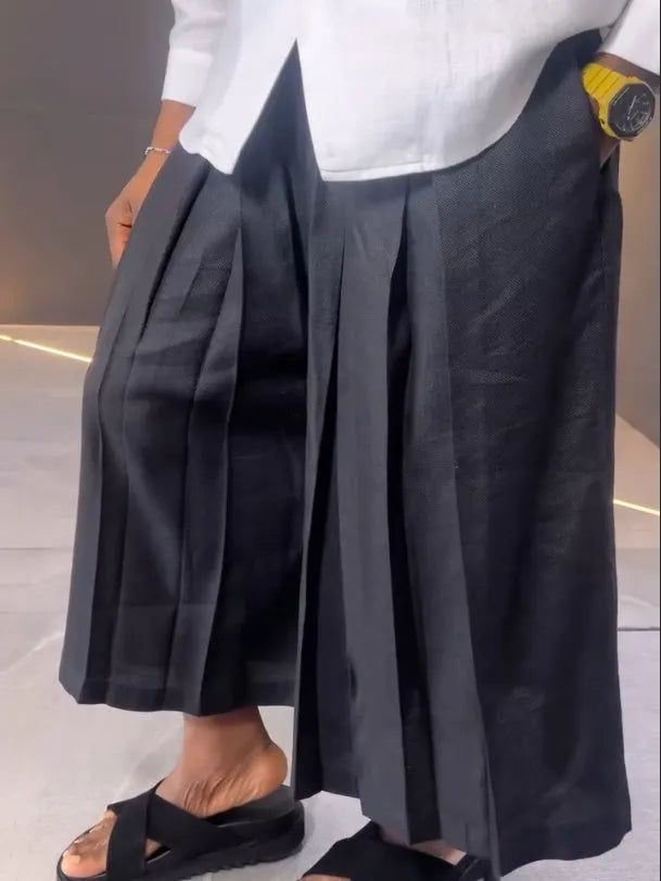 White asymmetric long sleeve shirt with black pleated pants set on a model for casual wear