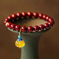 Handmade wave-shaped bracelet featuring cinnabar and copper beads on a wrist.