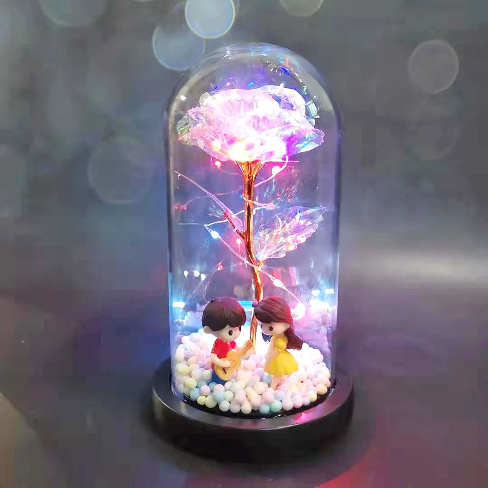 Gold artificial rose inside glass dome with LED lights on black base for home display