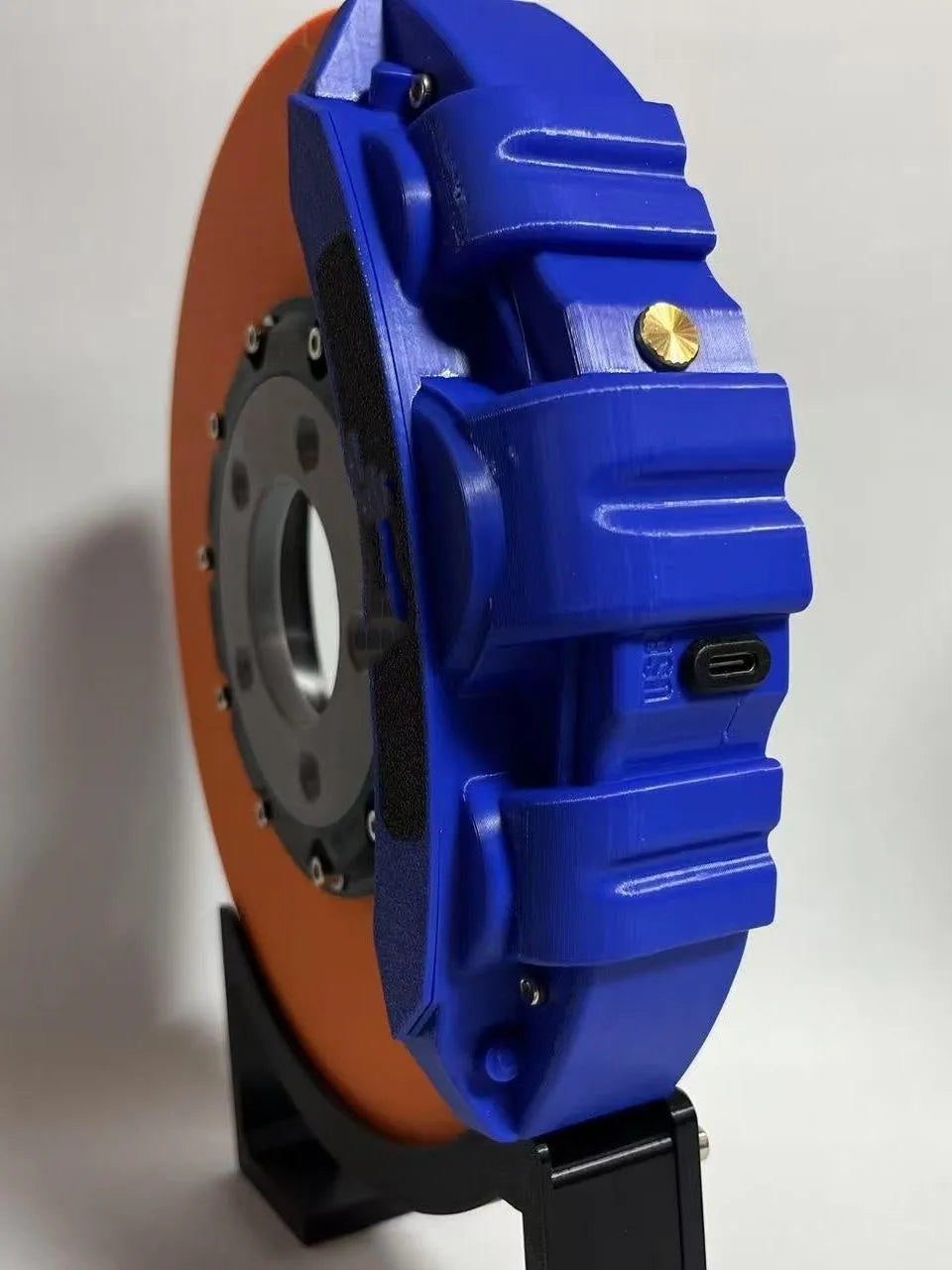 Rechargeable brake disc LED night light with touch dimmer, blue caliper colour, on a desk