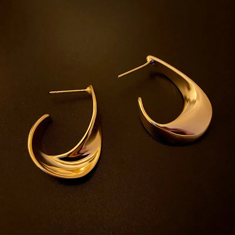 Gold twisted geometric metal earrings with round design elements
