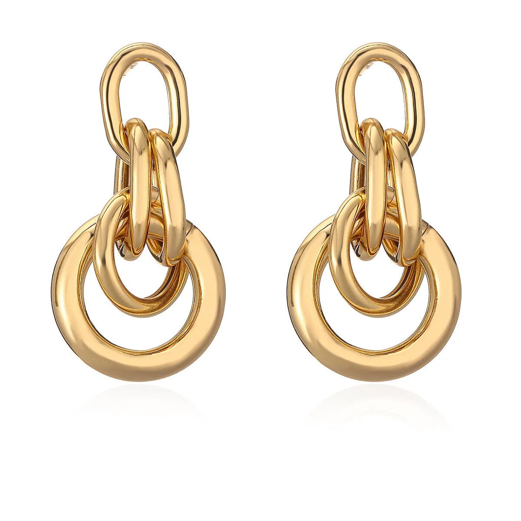 A pair of gold-coloured geometric copper earrings with irregular shapes on a white background.