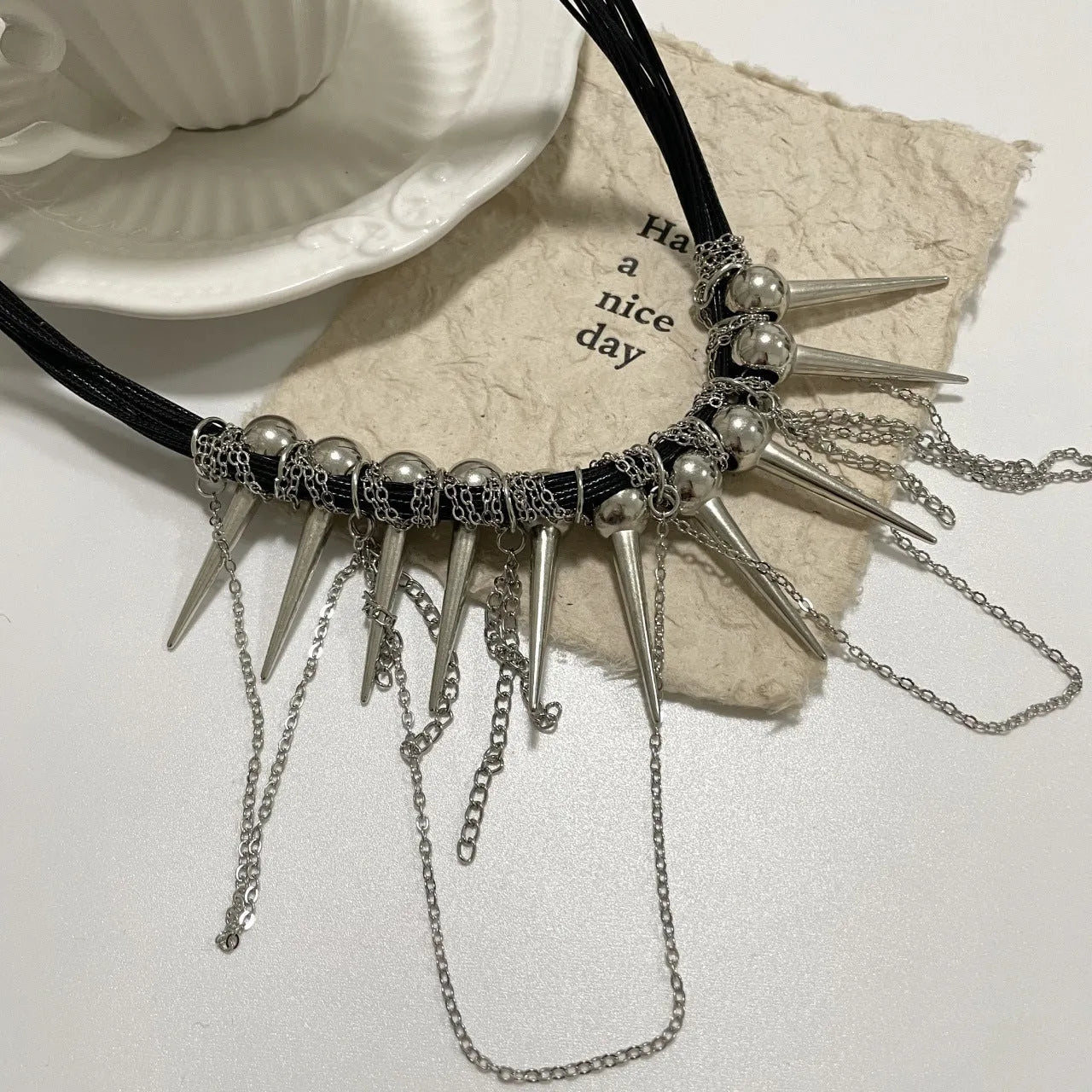 Leather necklace with winding tassel, round beads, and silver point rivet details.