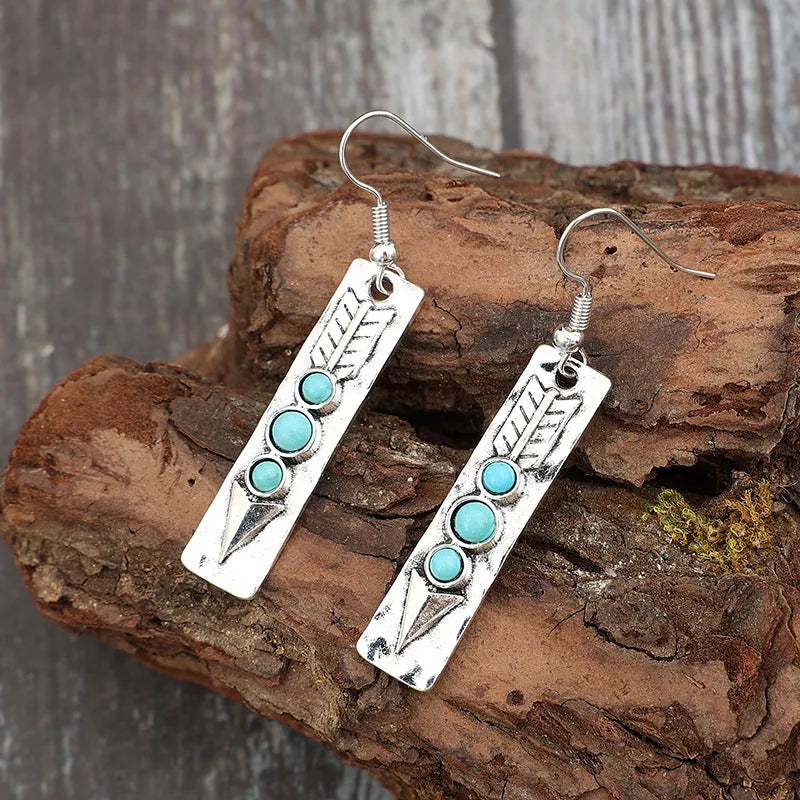 Long strip geometric silver earrings with inlaid turquoise detail on a white background