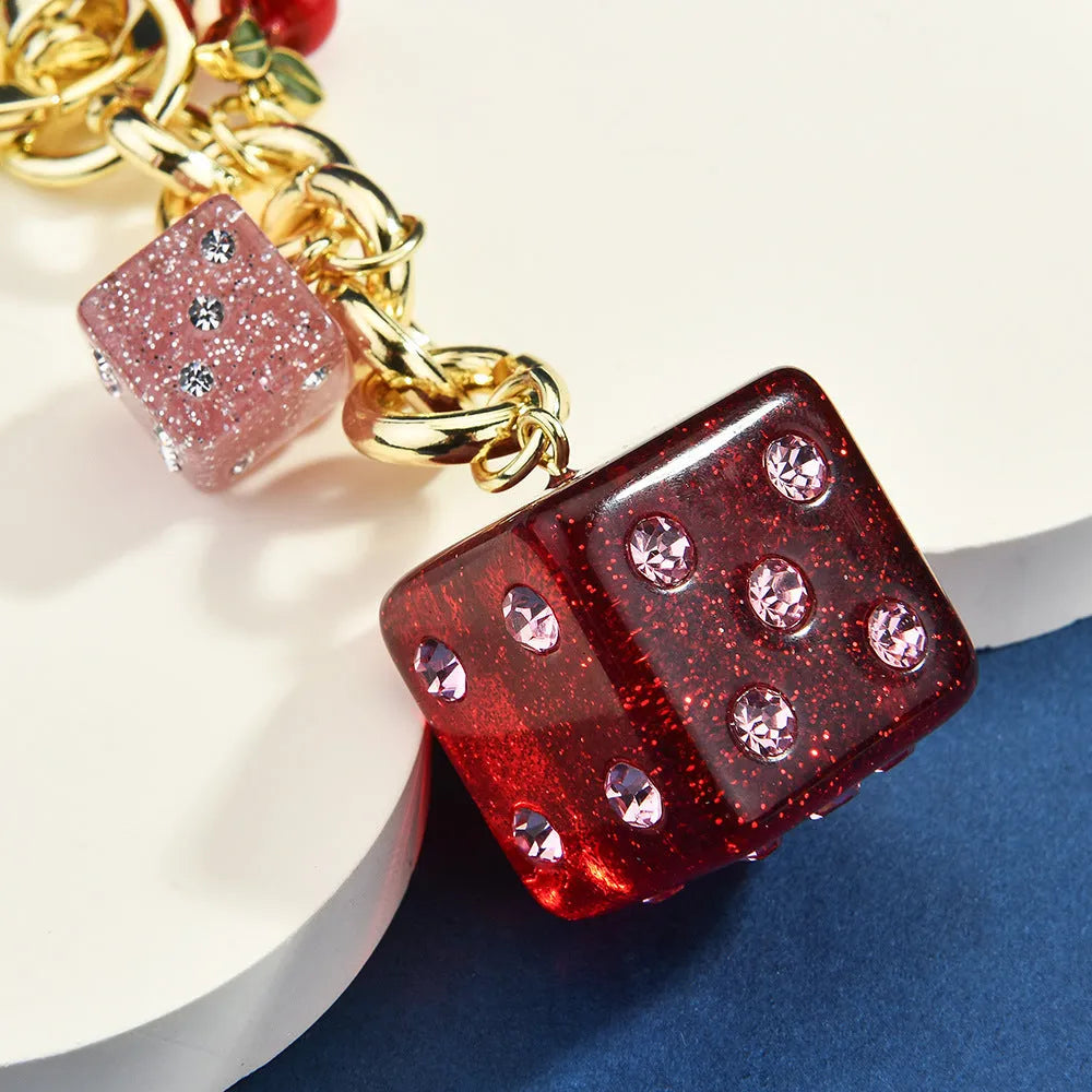 Close-up of a square metal keychain pendant with a vintage cherry two-tone dice pattern.