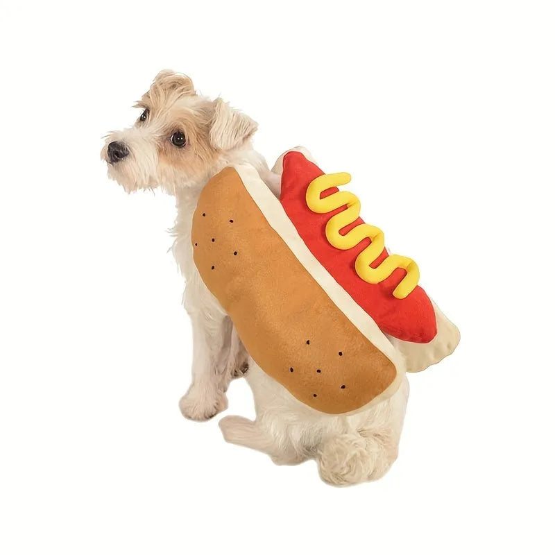 A small dog wearing a brown and beige plush hot dog costume with openings for head, legs, and tail.