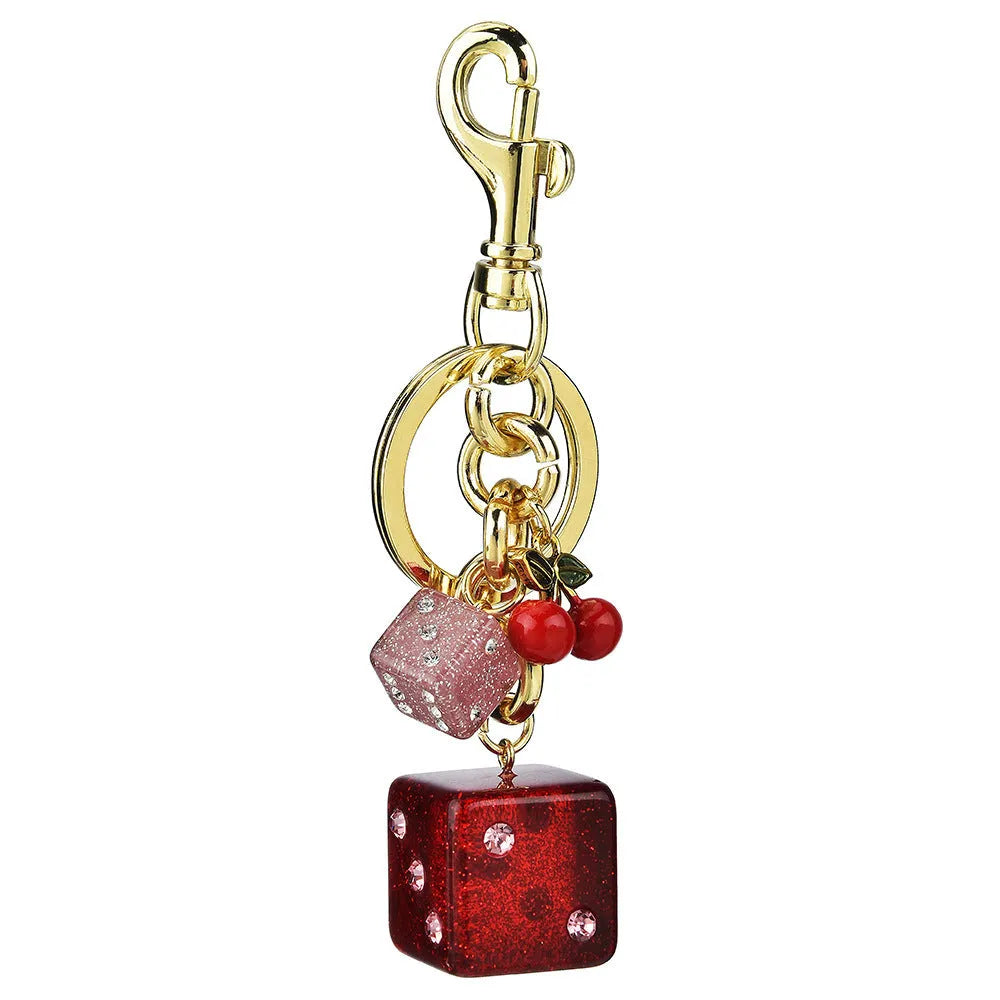 Close-up of a square metal keychain pendant with a vintage cherry two-tone dice pattern.
