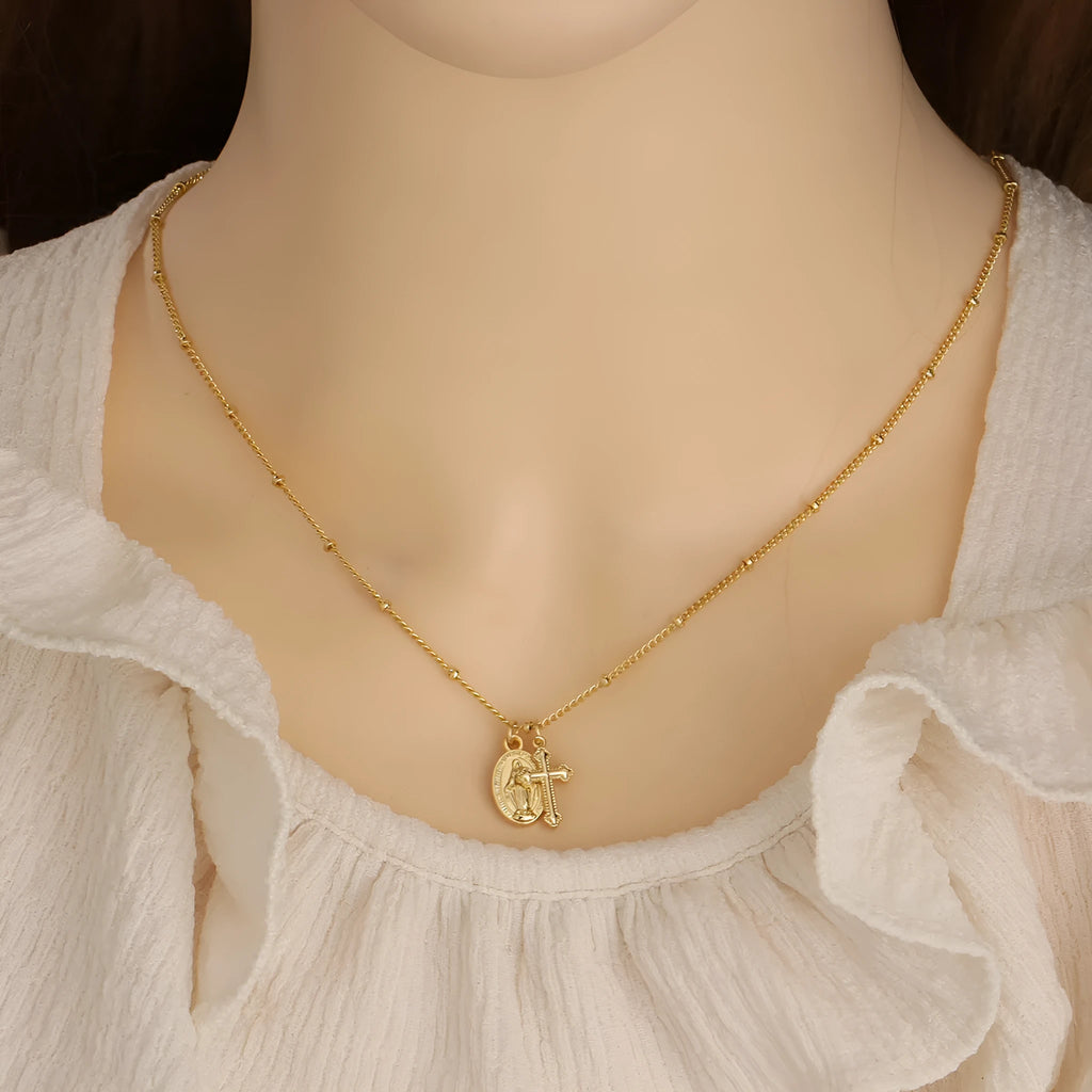 Gold geometric cross necklace with Virgin Mary ornament on a simple chain.