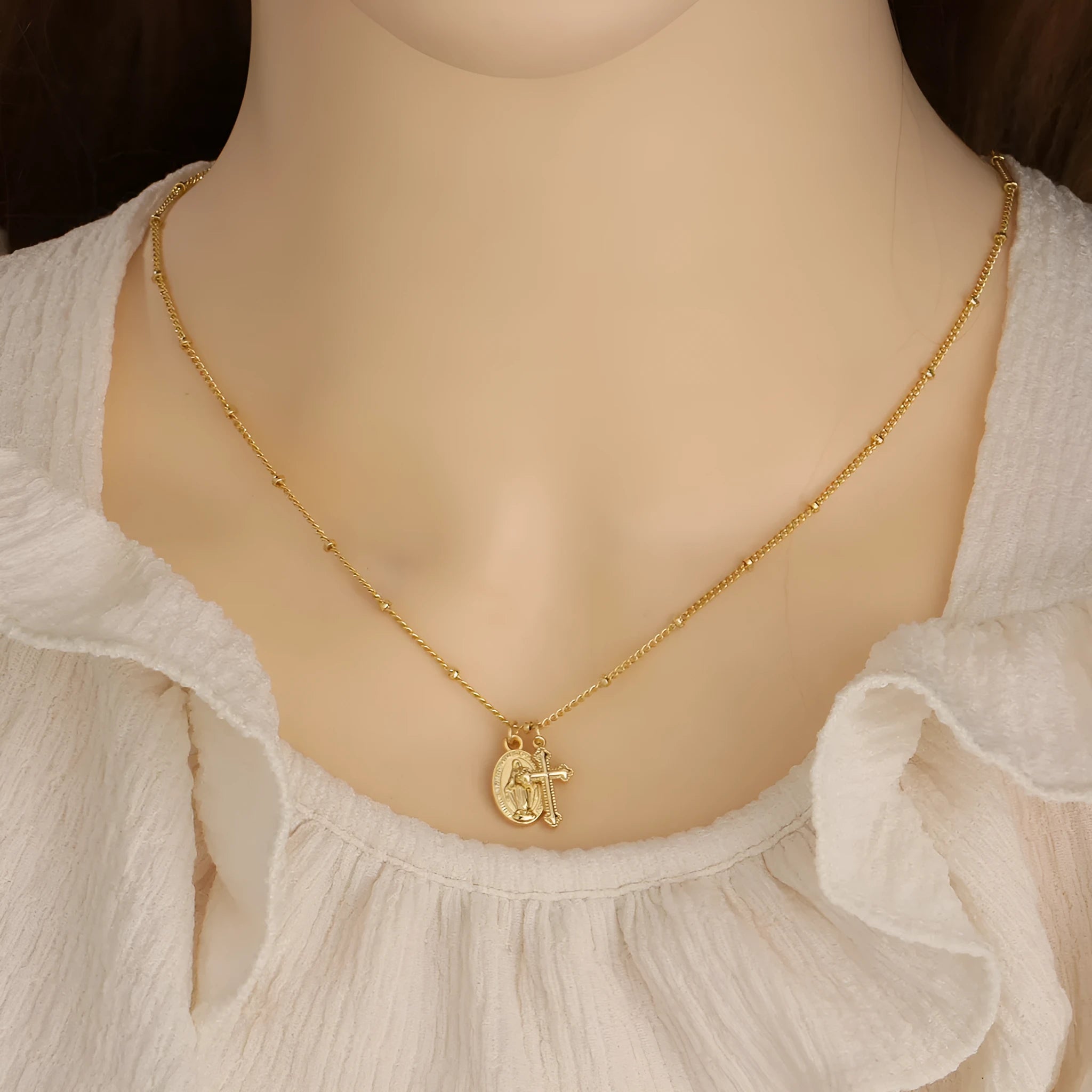 Gold geometric cross necklace with Virgin Mary ornament on a simple chain.