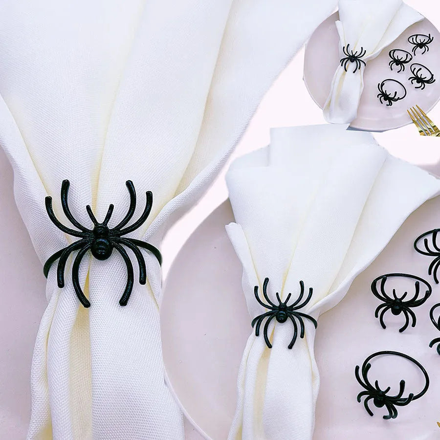 Six black alloy spider-shaped napkin rings for Halloween table decoration on a dark surface.