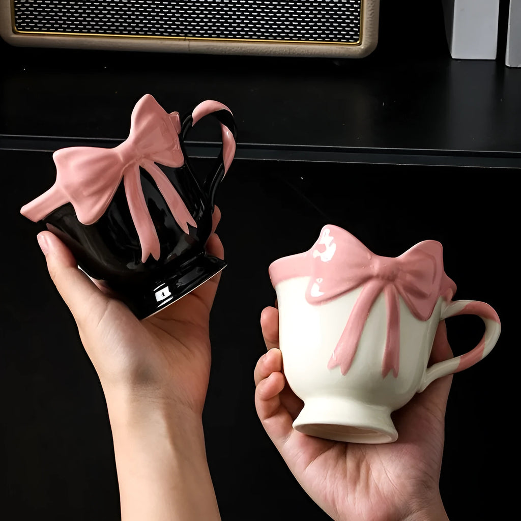 White ceramic mug with a pink heart and black bow design, 350ml capacity.