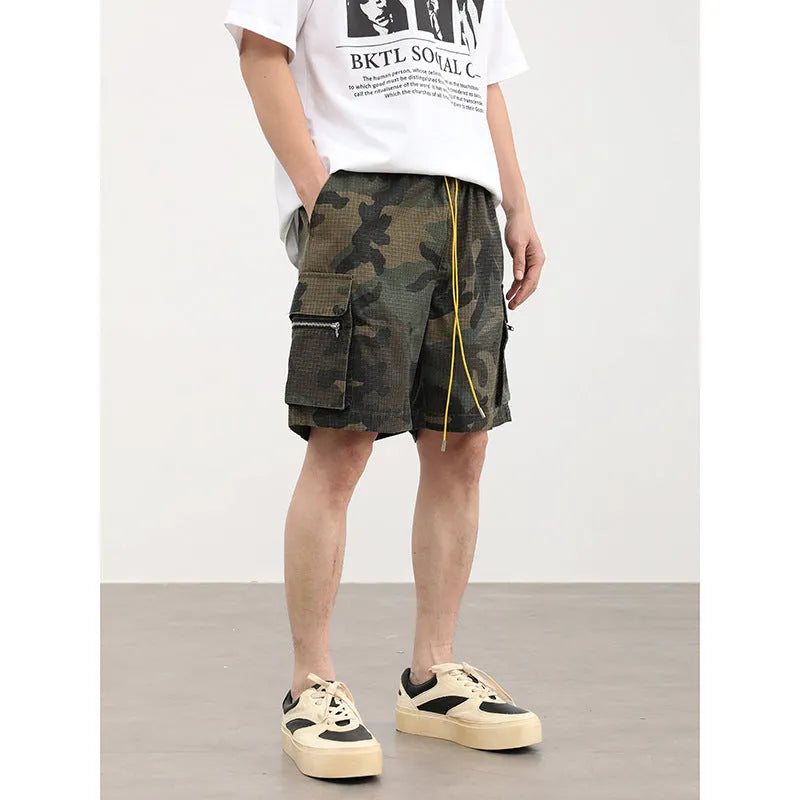 Multi-pocket camouflage workwear shorts for men with mid-waist cropped design and thin fabric, shown in a flat lay.