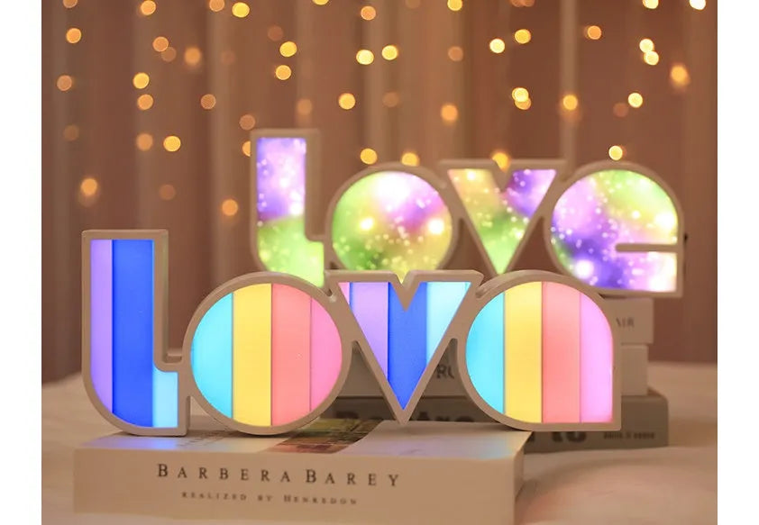 LED LOVE light with rainbow lampshade on a table against a dark background