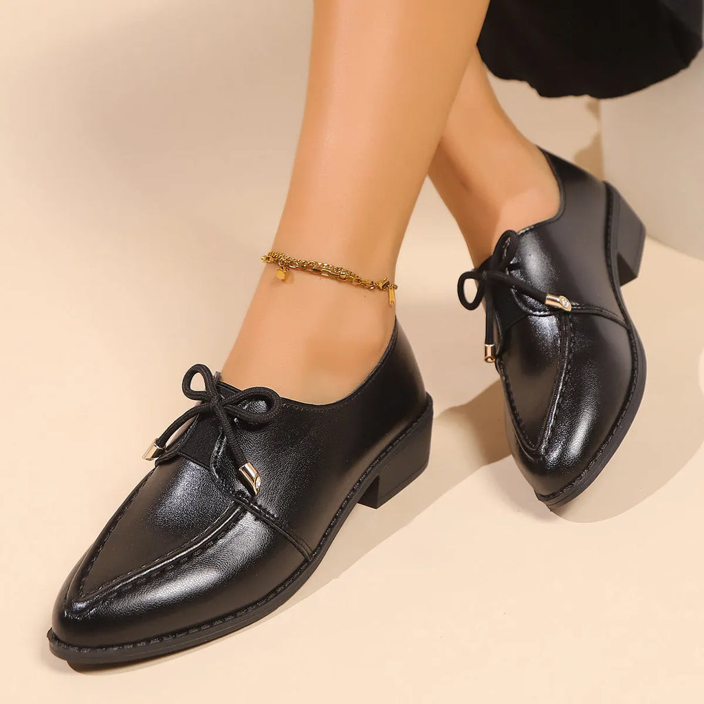 Women's leather-look slip-on shoes with decorative bow buckle detail and pointed toe