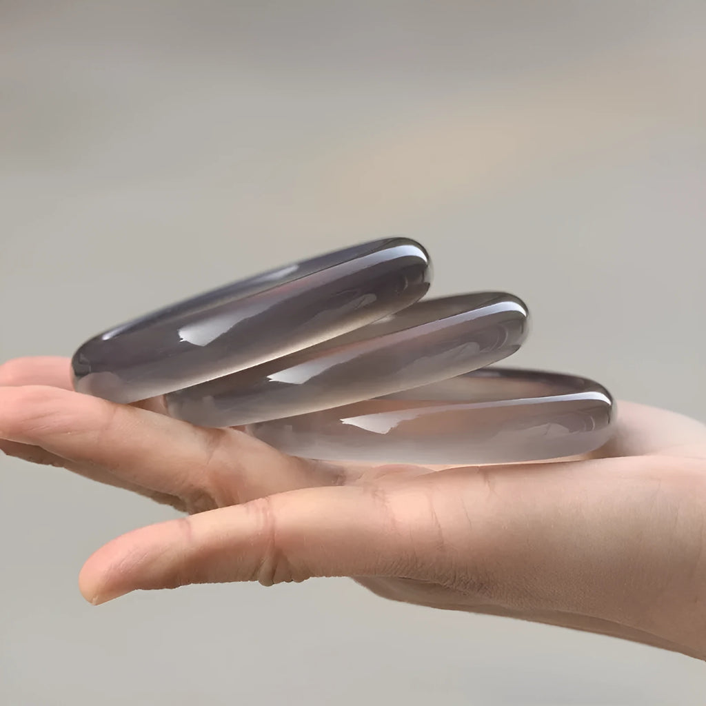 Dark gray iced chalcedony agate bracelet with Seiko finish on plain background showing natural stone texture