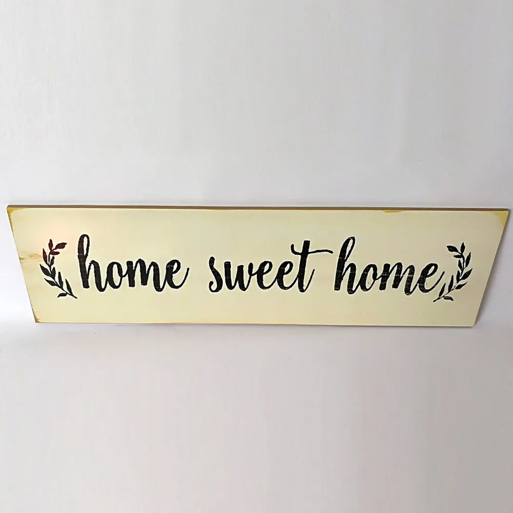 Home Sweet Home wooden carved pendant in black, 40cm x 12cm, hanging on a light wall