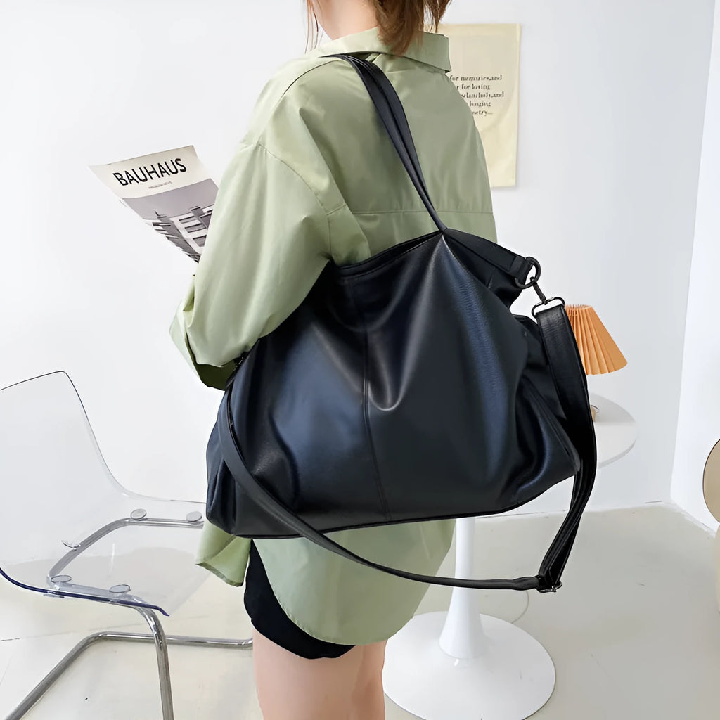 Large soft surface PU messenger bag in horizontal square shape with shoulder strap and top handle.