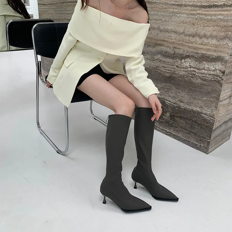 Black women's below-the-knee pointed toe stiletto boots with a back zipper on a white background