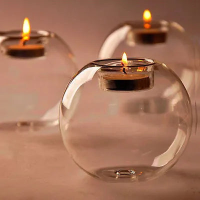 Handblown round hollow glass candle holder on a table, shown in frosted and clear finishes.