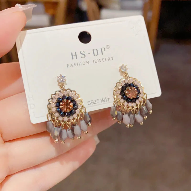 Pair of diamond embedded round crystal tassel earrings, thick gold plated, purple colour, on a white background