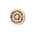 A round natural papyrus placemat with decorative tassels, shown on a wooden table.