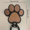 Wooden foot paw print hook in black colour on a white wall for household organisation