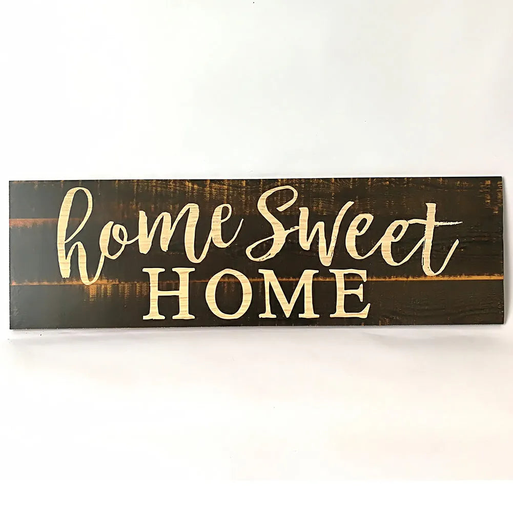 Home Sweet Home wooden carved pendant in black, 40cm x 12cm, hanging on a light wall