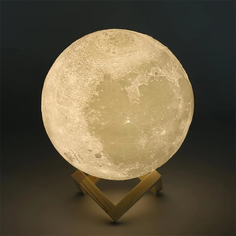3D printed white moon lamp with detailed craters on a wooden stand, glowing with warm yellow light.