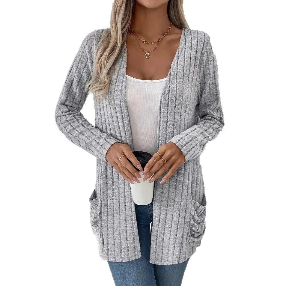 Man wearing a solid grey loose-fit long sleeve cardigan with side pockets.