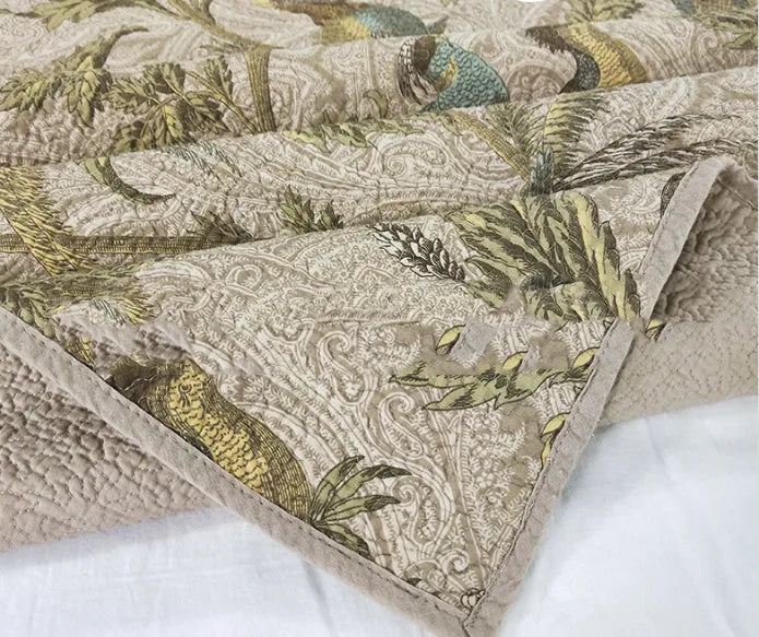 Blue cotton bedspread set with American floral and bird pattern laid on a bed.