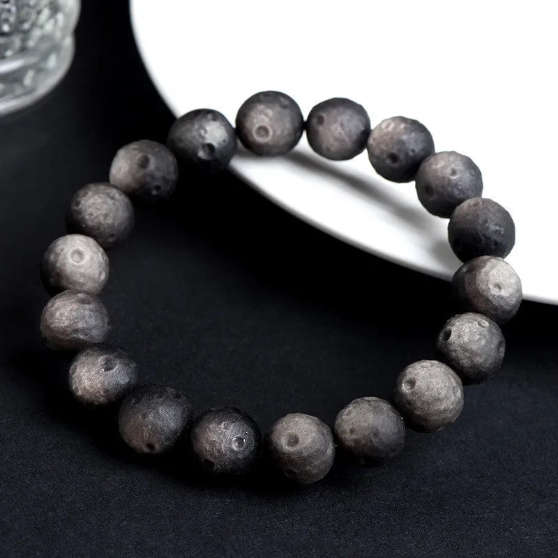 Natural obsidian crater ball bracelet in gold or silver meteorite finish on a wrist.
