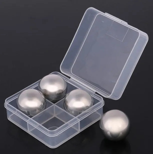 Set of 8 stainless steel ice cubes in square and ball shapes with plastic storage box and tong on a wooden surface