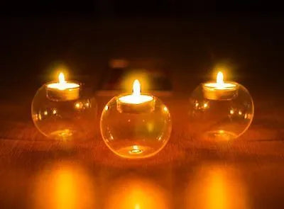 Handblown round hollow glass candle holder on a table, shown in frosted and clear finishes.