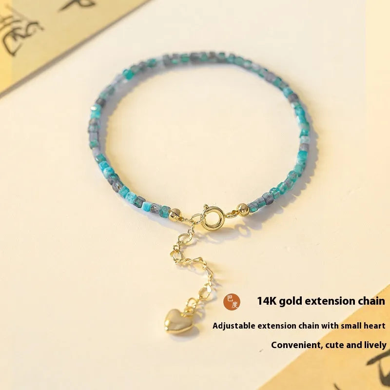 Natural blue apatite crystal bracelet with diamond-shaped beads, blue and grey colour, on a white background
