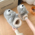 Pair of grey ankle wrap cotton slippers with plush upper and artificial wool lining on a home floor