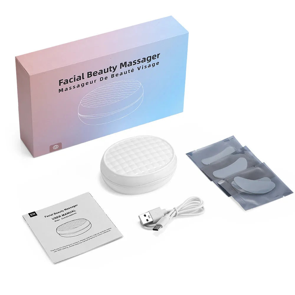 White wireless red light EMS facial and eye massager device on a table